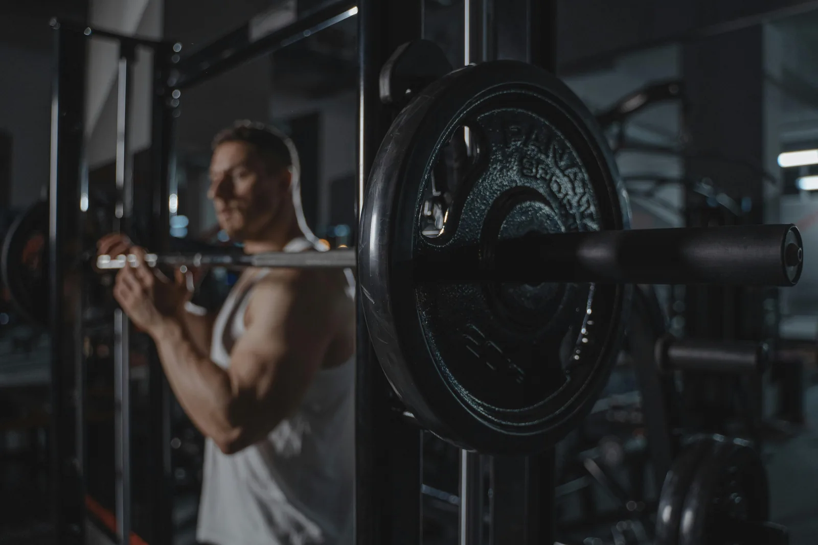 A loaded barbell resting on a rack in an empty gym